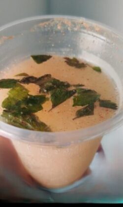 A vibrant glass of sweet and spicy grape fizz, garnished with fresh mint leaves and served with ice, showcasing a fizzy purple drink."